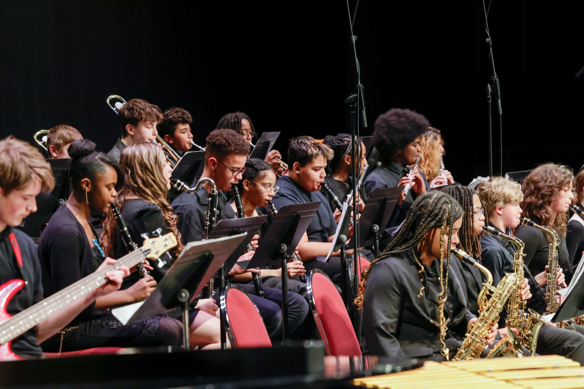 A group of musicians dressed in black perform on stage with various instruments.