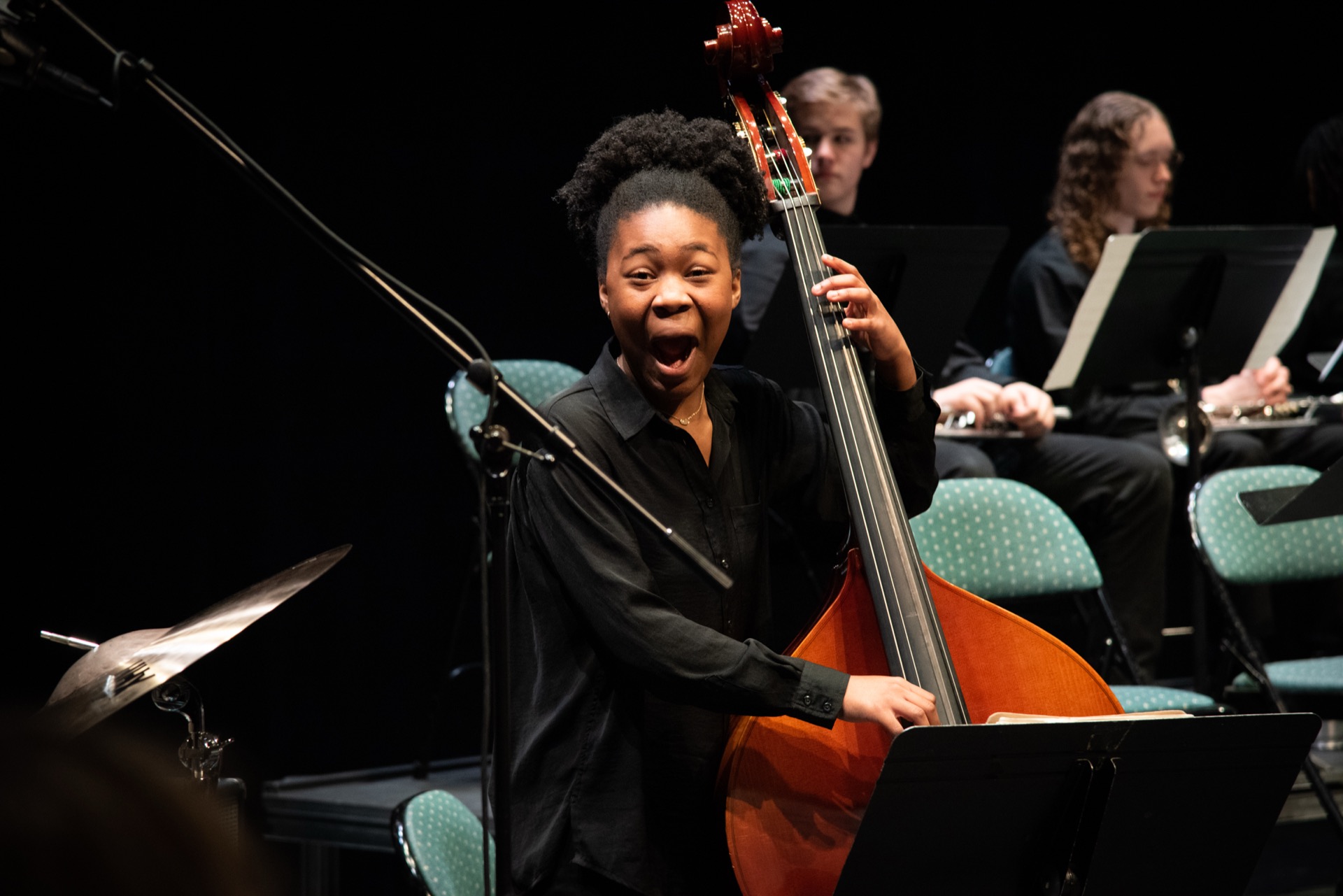 A musician passionately plays an upright bass on stage.