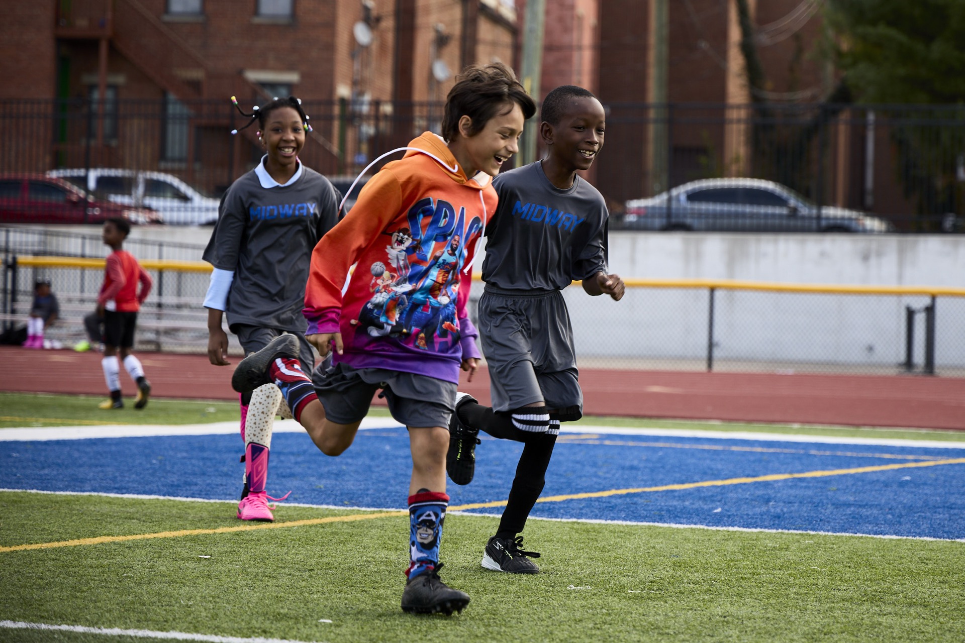 Children are joyfully running on a sports field.