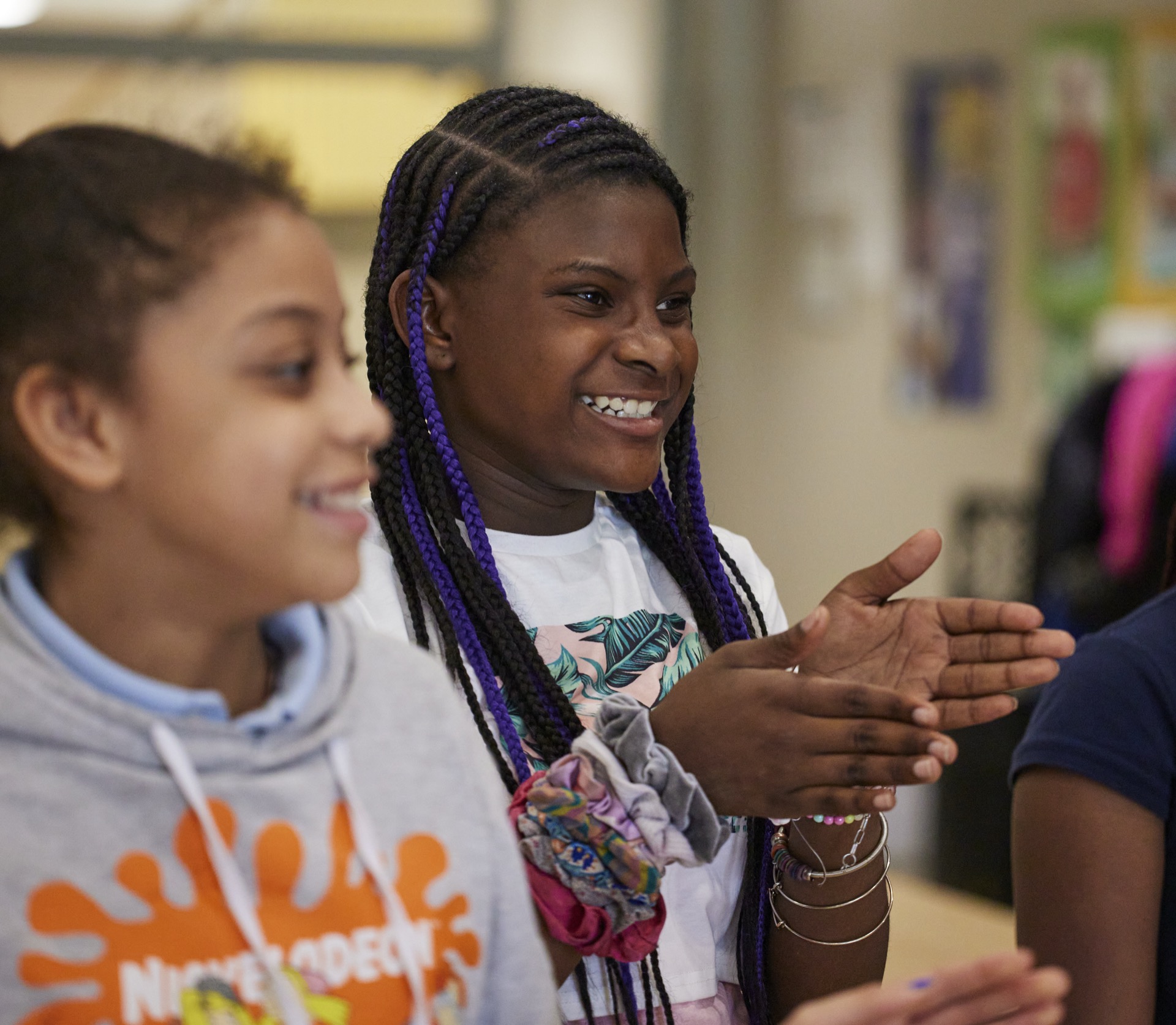 A group of young individuals is engaged in a lively conversation, with one person clapping hands enthusiastically.